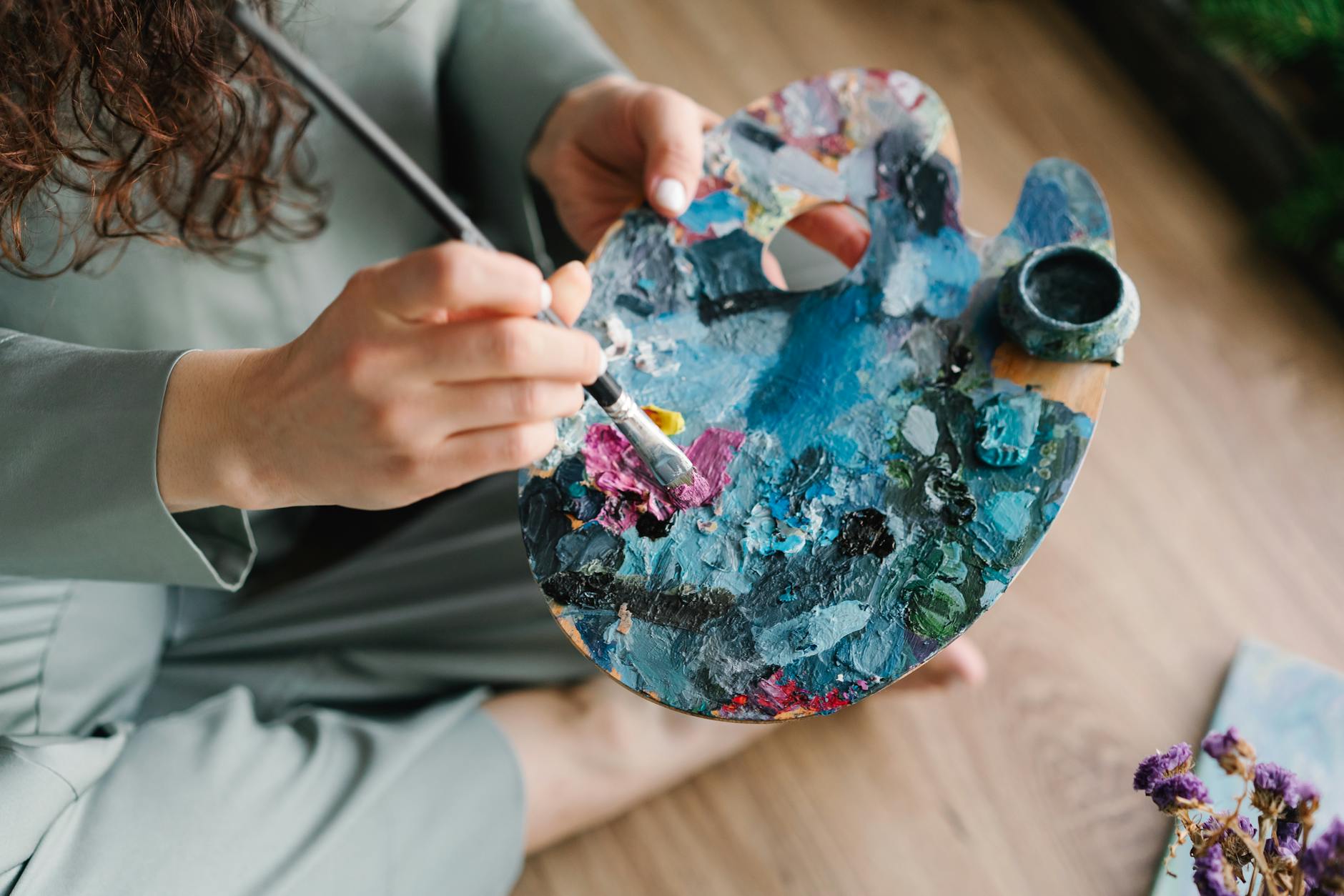 a person holding a brush and palette with colorful paint